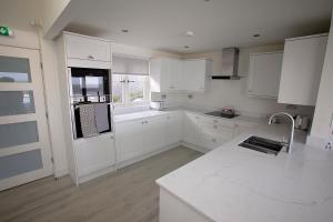 Una cocina con gabinetes blancos y una encimera blanca. en Filey Beach House, en Filey