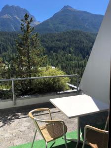 einen Tisch und zwei Stühle auf einem Balkon mit Bergblick in der Unterkunft Tulai G98 in Scuol