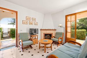 Torres Sureda في كالا بلانكا: غرفة معيشة مع أريكة وكراسي ومدفأة