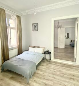 a white bedroom with a bed and a large mirror at CRYSTAL Św. Marcin Poznań in Poznań