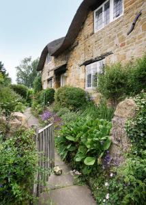 Casa de piedra con valla y jardín en Letterbox Cottage en Chipping Campden
