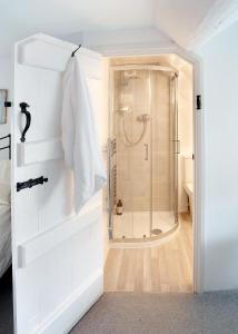 ein Bad mit einer Dusche und einer weißen Tür in der Unterkunft Letterbox Cottage in Chipping Campden