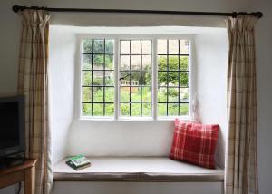 un asiento junto a la ventana con una almohada roja delante en Letterbox Cottage, en Chipping Campden