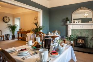 a dining room with a table with food and a fireplace at Corriness House in Poolewe