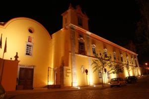 a large white building with a clock tower at night at Pousada Convento de Tavira in Tavira