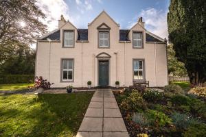 een groot wit huis met een voortuin bij Corriness House in Poolewe