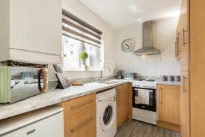 a kitchen with a washing machine and a sink at Luxury 3-Bed Apartment Near To London With Parking in Hornchurch