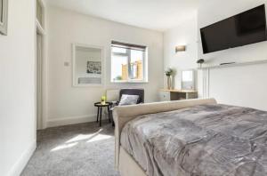 a bedroom with a bed and a flat screen tv at Luxury 3-Bed Apartment Near To London With Parking in Hornchurch