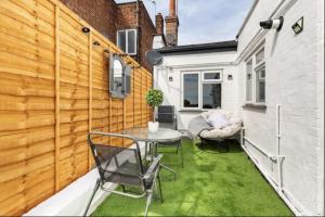 een kleine achtertuin met een tafel en stoelen op een patio bij Luxury 3-Bed Apartment Near To London With Parking in Hornchurch