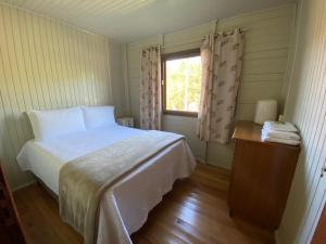 um quarto com uma cama branca e uma janela em Pousada Costão da Serra em Lauro Müller