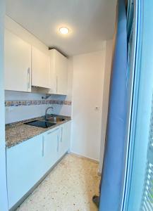 a kitchen with white cabinets and a sink at Aptos La Costera in Benidorm