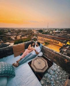 a couple sitting on a couch on top of a building at Mandawa Kothi in Mandāwa