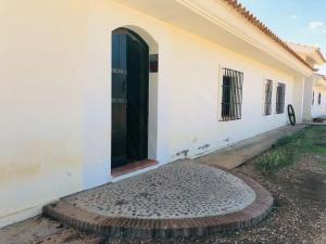 Casa blanca con puerta negra y entrada en Cortijo Los Lomillos - La Encina, 