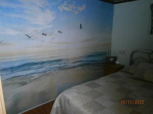 1 dormitorio con una pintura del océano en la pared en Chez Rose et Patrick, en Polícar