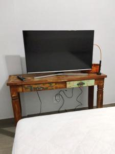 Apartamento aconchegante no Sudoeste في برازيليا: تلفزيون فوق طاولة خشبية بجانب سرير