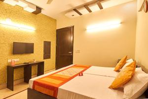 a bedroom with a bed and a desk and a television at OYO 3594 Kamla Nagar in New Delhi