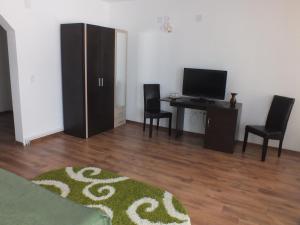 uma sala de estar com uma secretária com 2 cadeiras e uma televisão em Pensiunea Eliza em Podu Coşnii