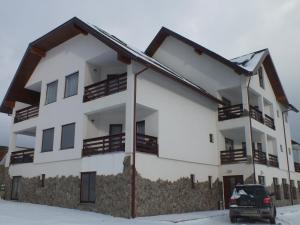an apartment building with a car parked in front of it at Pensiunea Eliza in Podu Coşnii