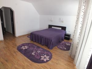 a bedroom with a bed and two rugs on the floor at Pensiunea Eliza in Podu Coşnii