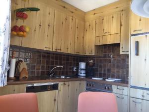 a kitchen with wooden cabinets and pink chairs in it at Ferienwohnung im Haus Primula in Obersaxen