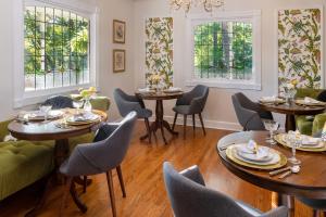 - une salle à manger avec des tables, des chaises et des fenêtres dans l'établissement Arsenic and Old Lace Bed & Breakfast Inn, à Eureka Springs