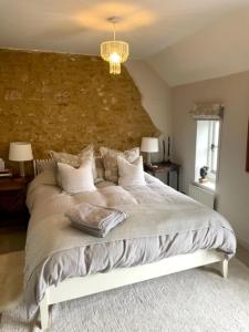 ein Schlafzimmer mit einem großen Bett und einer Steinmauer in der Unterkunft Idyllic Country Cottage near Soho, Oxford & Cotswolds in Banbury