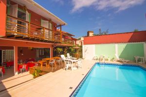 a house with a pool and a patio with a table and chairs at Pousada Irashai in Juquei