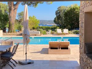 un patio con mesa y sombrilla junto a la piscina en Lovely "Provence" villa with sea view, private heated pool, airco and beautiful garden en Grimaud
