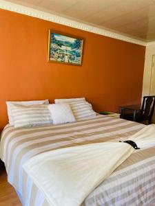 a large bed in a room with an orange wall at Village Retreat Ngcamngeni in Debe Nek