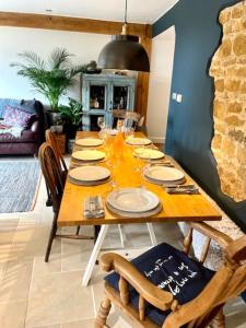 a dining room table with plates and glasses on it at Idyllic Country Cottage near Soho, Oxford & Cotswolds in Banbury
