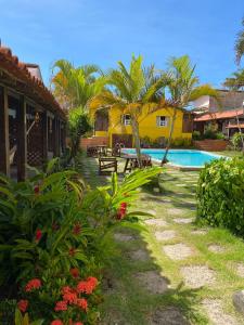 um pátio de resort com piscina e palmeiras em Pousada das Gaivotas em Guaibim