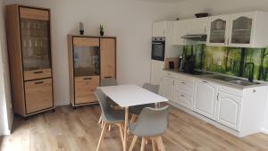 uma cozinha com armários brancos e uma mesa e cadeiras em Naturferienhof Märkisch Luch 