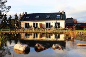 a house with a reflection in a pond at Naturferienhof Märkisch Luch - a64537 