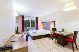 a hotel room with a bed and a desk with a computer at Garden & City Aix En Provence - Rousset in Rousset