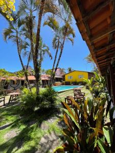 a view from the porch of a resort with palm trees and a swimming pool at Pousada das Gaivotas in Guaibim