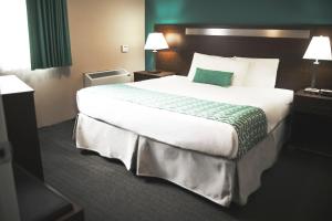 a large bed in a hotel room with a green accent at Ramada by Wyndham in Quesnel