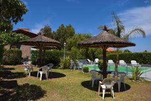 un grupo de sillas y sombrillas junto a una piscina en Cabañas El Regreso en Merlo