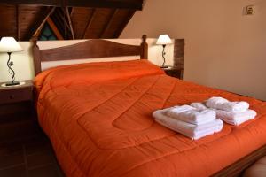 Una cama naranja con dos toallas encima. en Cabañas El Regreso en Merlo