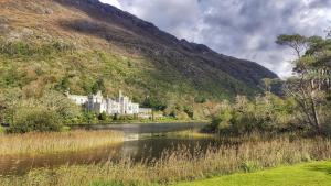 a castle in the middle of a river with a mountain at Clifden White Heather- 3 Bedroom House in Clifden