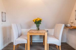 een tafel met twee stoelen en een vaas met bloemen erop bij Haus Kähler 1 Wohnung 7 in Büsum