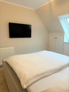 sypialnia z łóżkiem z telewizorem na ścianie w obiekcie Dünen Lodge w mieście Westerland