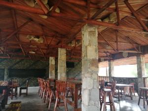 uma sala de jantar com tectos e mesas e cadeiras de madeira em Murchison Backpackers em Masindi