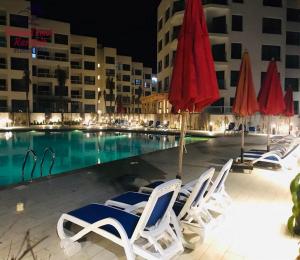 a group of chairs and umbrellas next to a pool at شاليهات فندقيه بورتوسعيد in Port Said