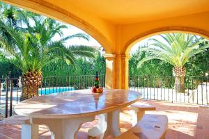 a patio with a table and two palm trees at Villa Fustera - PlusHolidays in Benissa