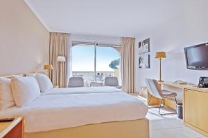 Cette chambre comprend un grand lit et un bureau. dans l'établissement Van der Valk Hotel Barcarola, à Sant Feliu de Guíxols