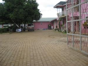 ein rosafarbenes Gebäude mit einer steinernen Einfahrt davor in der Unterkunft R&R Gardens Hotel in Mbale