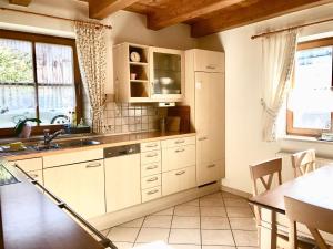 ヴァーギング・アム・ゼーにあるSeehäuschen - Waging Tettenhausenの白いキャビネット、シンク、テーブル付きのキッチンが備わります。