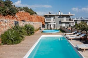 - une piscine avec des chaises longues à côté d'un bâtiment dans l'établissement Amina villa, à Agios Nikolaos