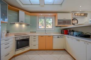 una cocina con armarios blancos y naranjas y una ventana en Amina villa, en Agios Nikolaos