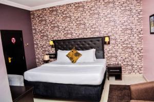 - une chambre avec un grand lit et un mur en briques dans l'établissement Shamrockmanor(TheResidence), à Benin City